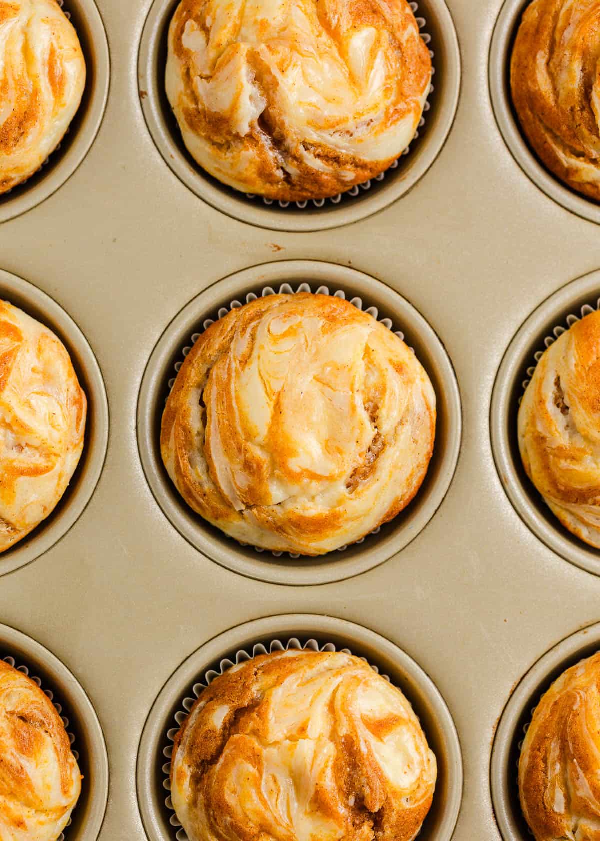 Pumpkin cream cheese muffins in a muffin pan.