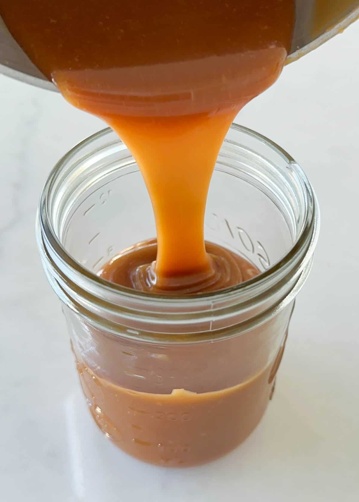 Pouring easy caramel sauce into jar.