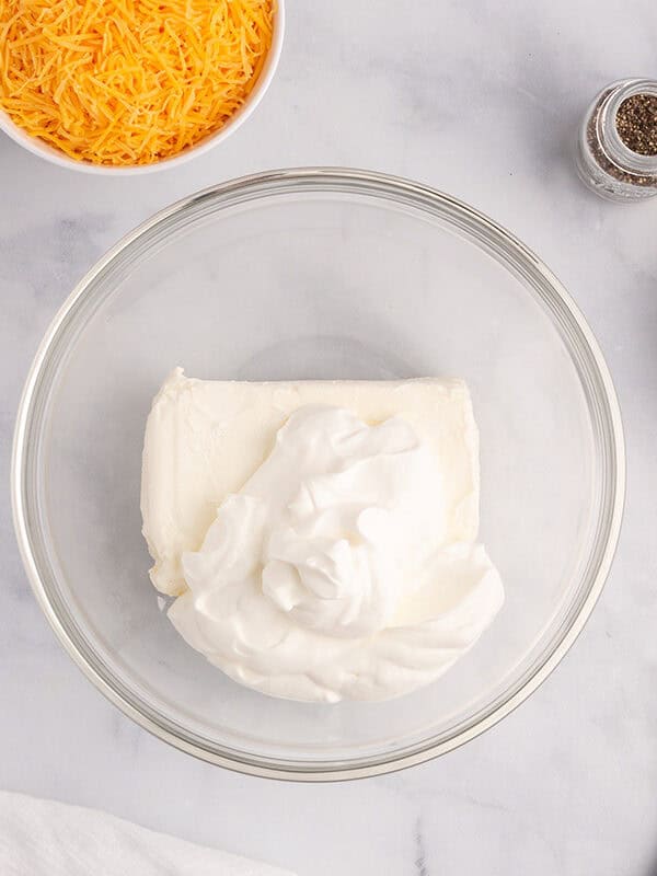 Cream cheese and sour cream in a glass bowl.