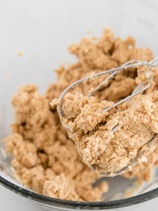 Peanut butter, butter, vanilla and powdered sugar in a bowl with beaters.