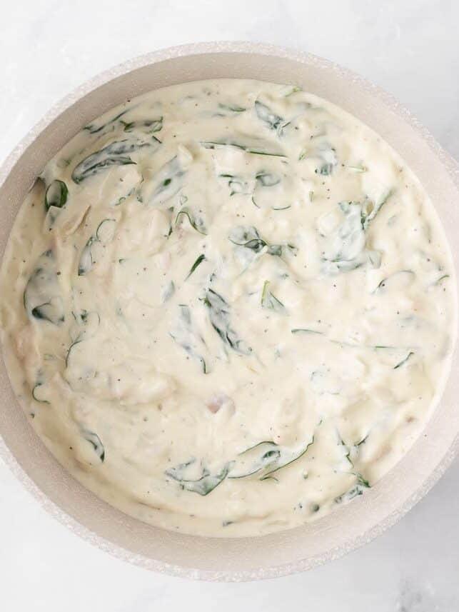 Alfredo sauce with spinach in a pot.