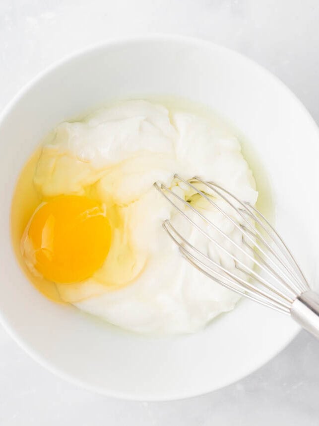 Egg and ricotta whisked together in a bowl.