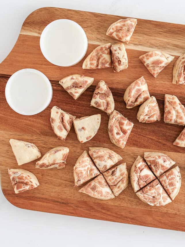 Cinnamon rolls cut into 4 pieces on cutting board.