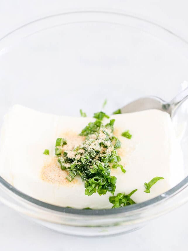 Cream cheese in a bowl with seasonings. 