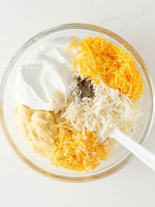 Hashbrowns, cheese, sour cream and cream of chicken soup in a glass dish.