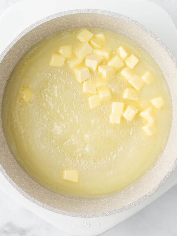 Cubed butter added to a pot on the stove.