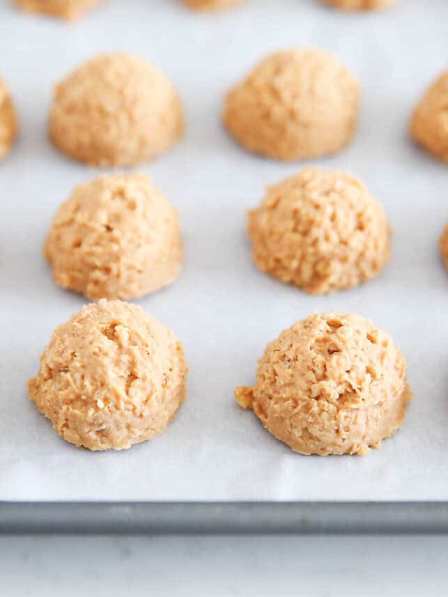 Rice Krispie peanut butter balls on a parchment lined baking sheet.