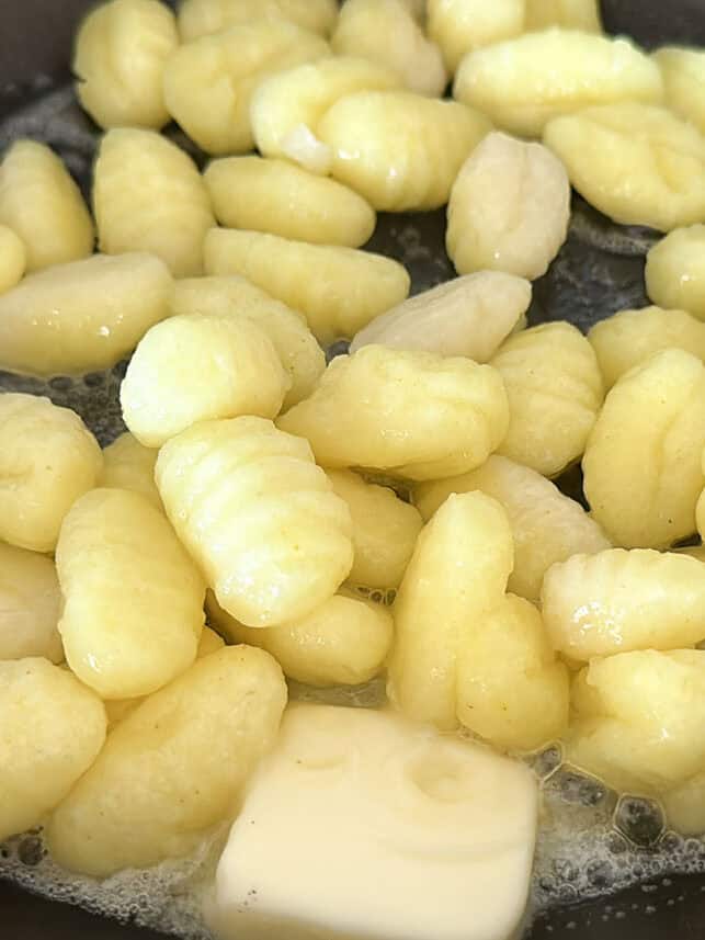 Melting butter with gnocchi in a skillet.