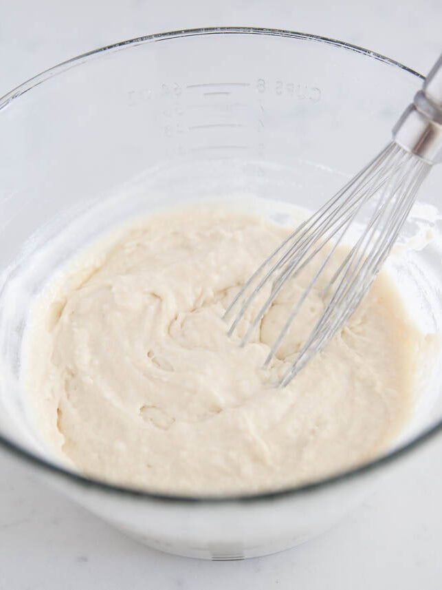 Silver dollar pancake batter with whisk in glass bowl.