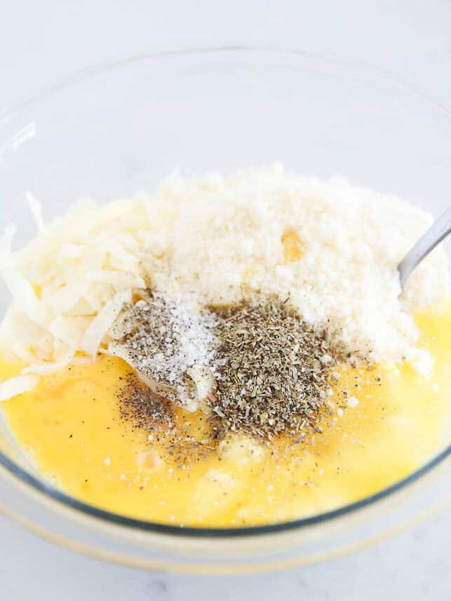 Cheese, seasonings and ricotta with eggs in a bowl.