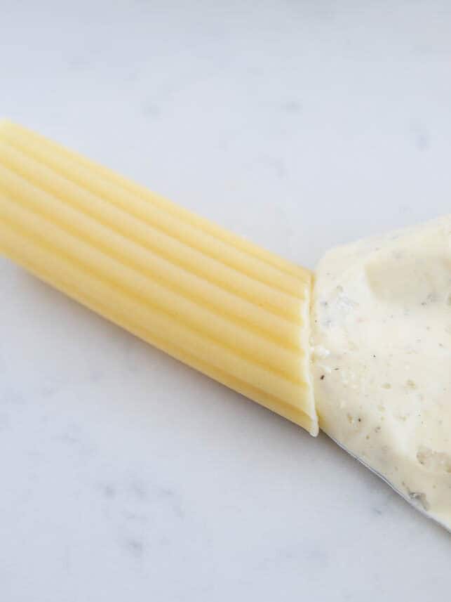 Ricotta filling in a bag being piped into a manicotti tube. 