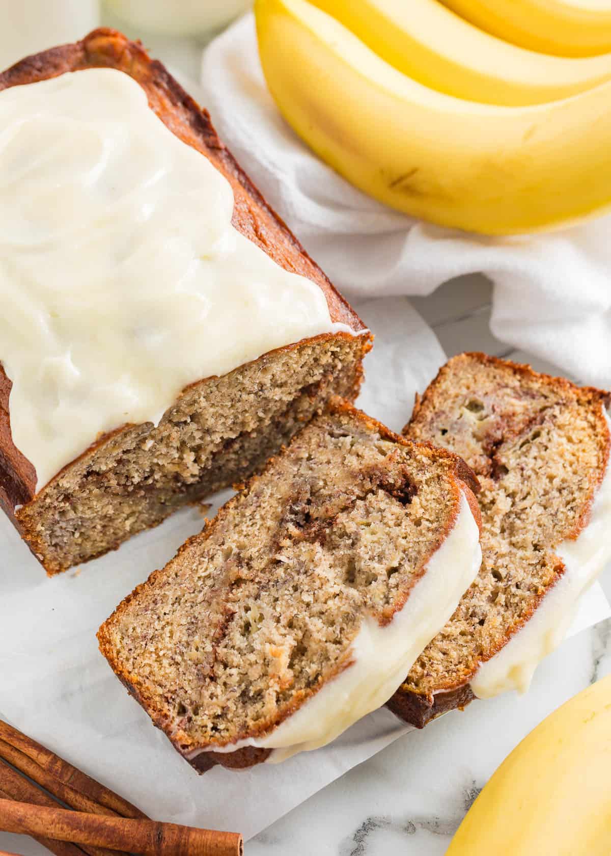 Sliced cinnamon roll banana bread with cream cheese frosting.