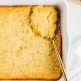 Jiffy corn pudding in white pan with spoon.