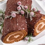 Yule log cake with cranberries on top.