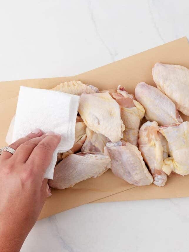 Patting chicken wings dry with paper towel.