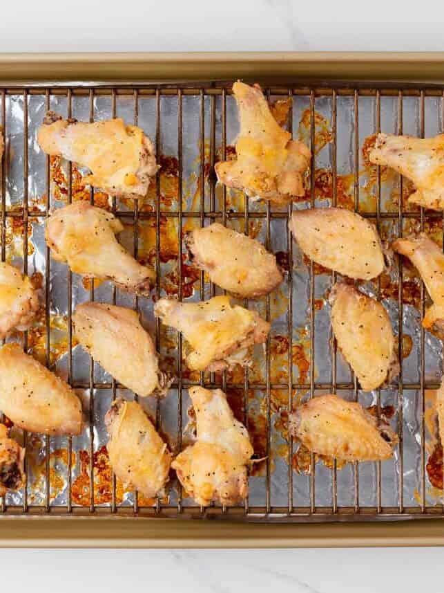 Crispy baked chicken wings in the oven set on a wire rack on a baking sheet.