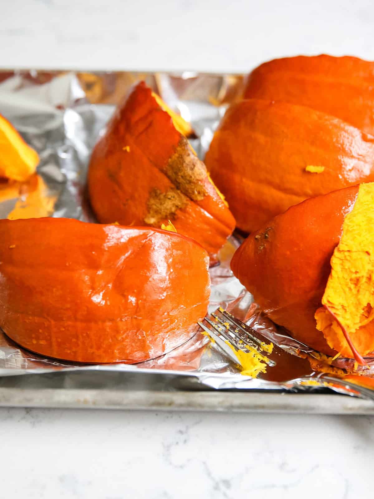 Pumpkin pieces on a baking sheet lined with foil.