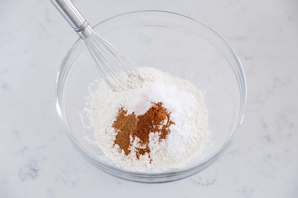 Flour, sugar, pumpkin spice and cinnamon in a bowl with baking staples.