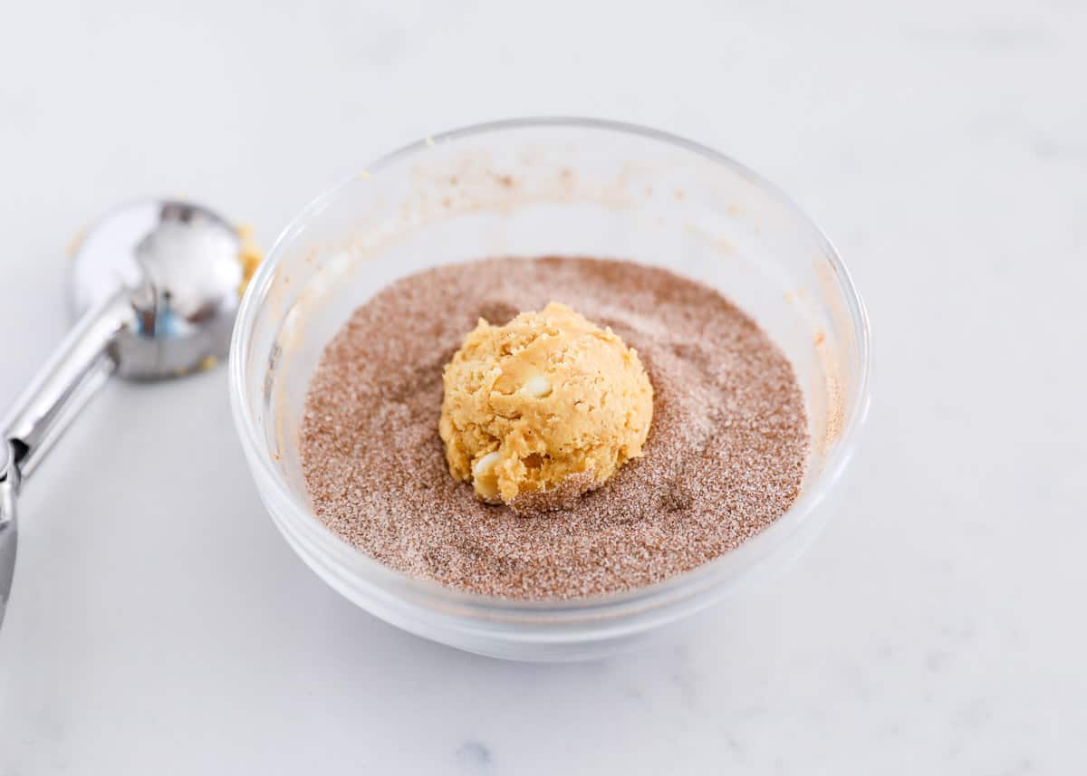 Rolling a cookie dough ball in cinnamon sugar.