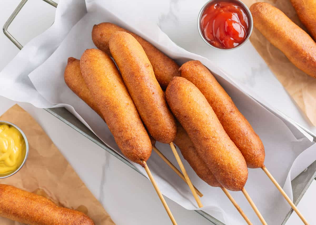 Corn dogs in a metal tin.