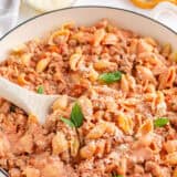 Ground turkey pasta in a large white skillet with serving spoon.