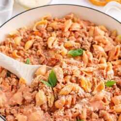 Ground turkey pasta in a large white skillet with serving spoon.