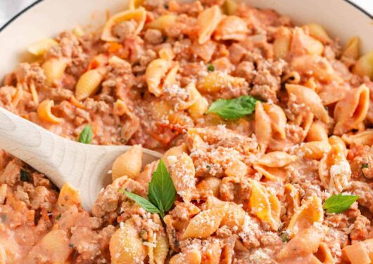 Ground turkey pasta in a large white skillet with serving spoon.