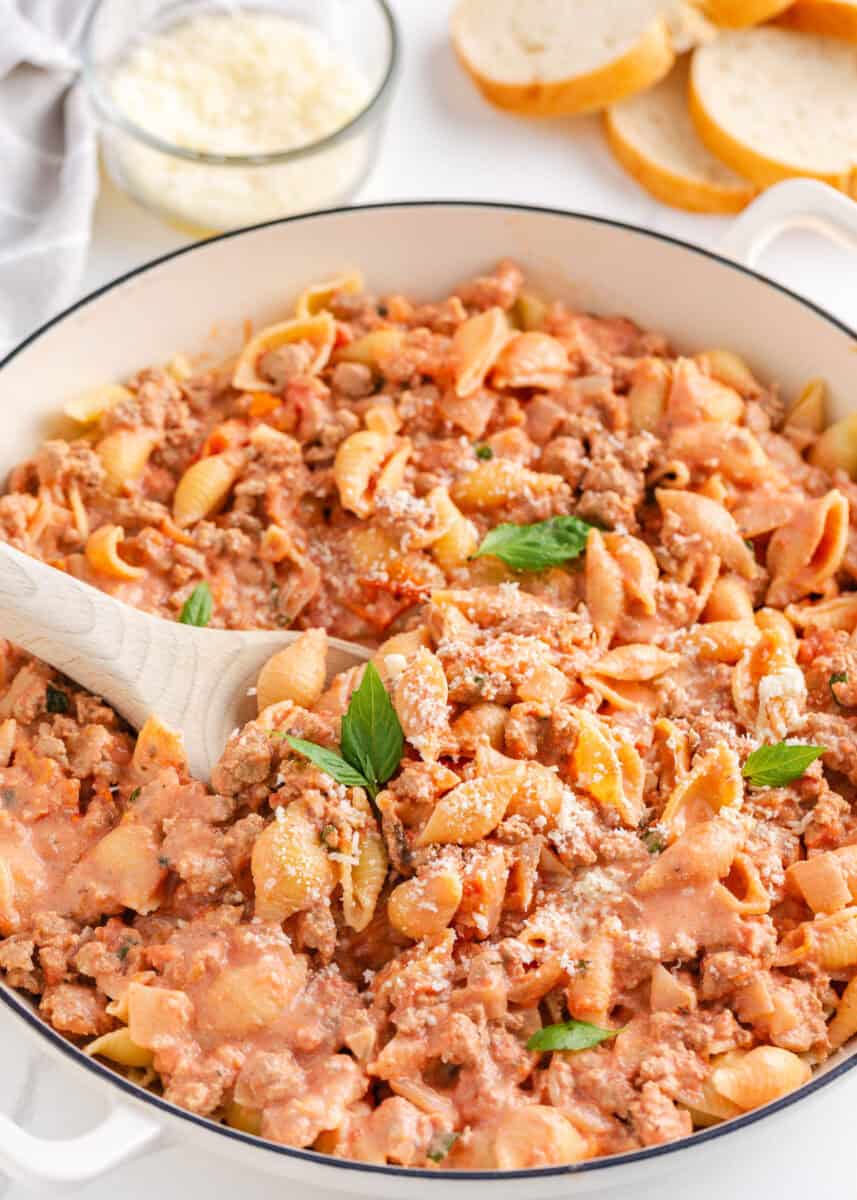 Ground turkey pasta in a large white skillet with serving spoon.