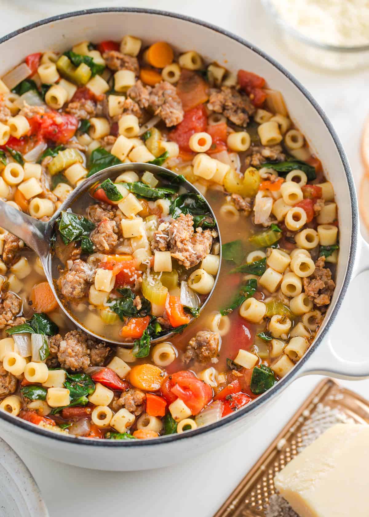 A pot with ladle serving Italian sausage pasta soup.