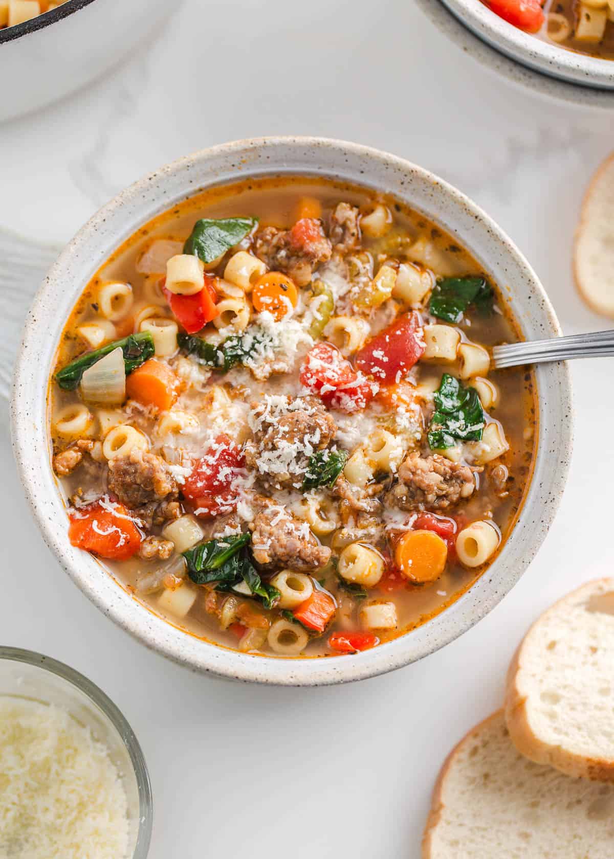 Italian sausage soup with pasta and spinach in a bowl.