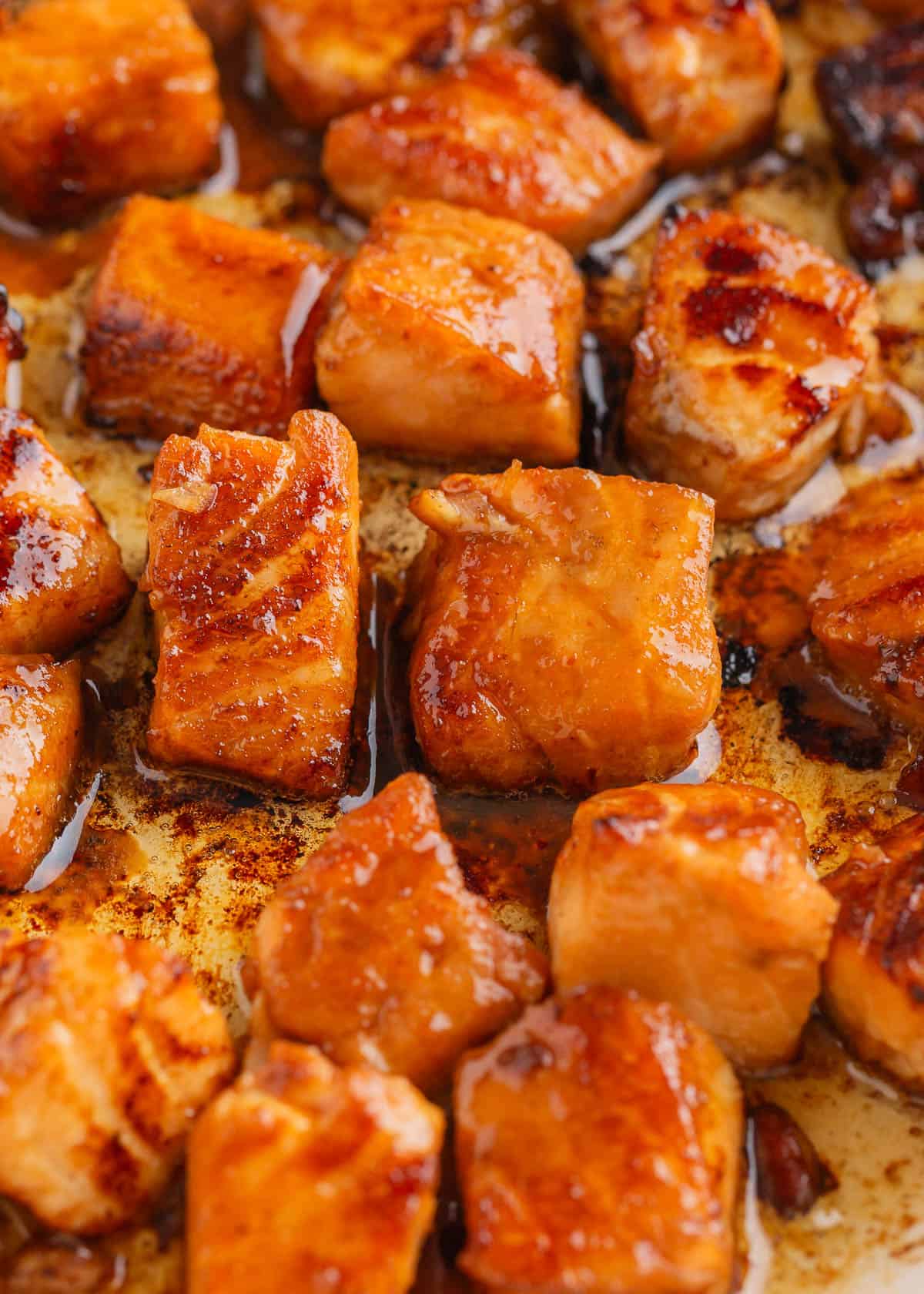 Salmon bites cooking in pan.