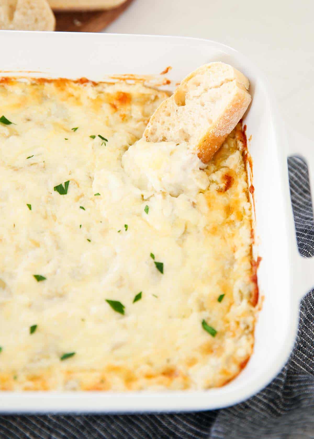 Baked artichoke dip in a white dish.