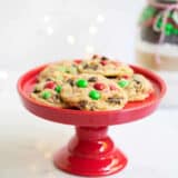 Homemade Christmas food gift idea, cookie mix in a jar with baked cookies on a red cookie stand.