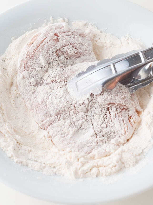 Dredging chicken in flour.