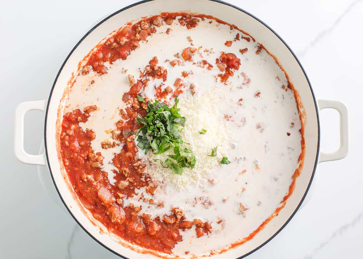 Adding cream and fresh herbs into large skillet with ground turkey mixture.