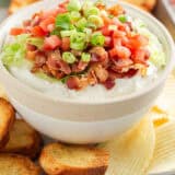 BLT dip in a bowl with crostini and chips on a platter.