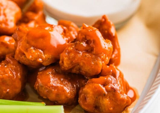 Boneless chicken wings on a serving plate with dip and celery.