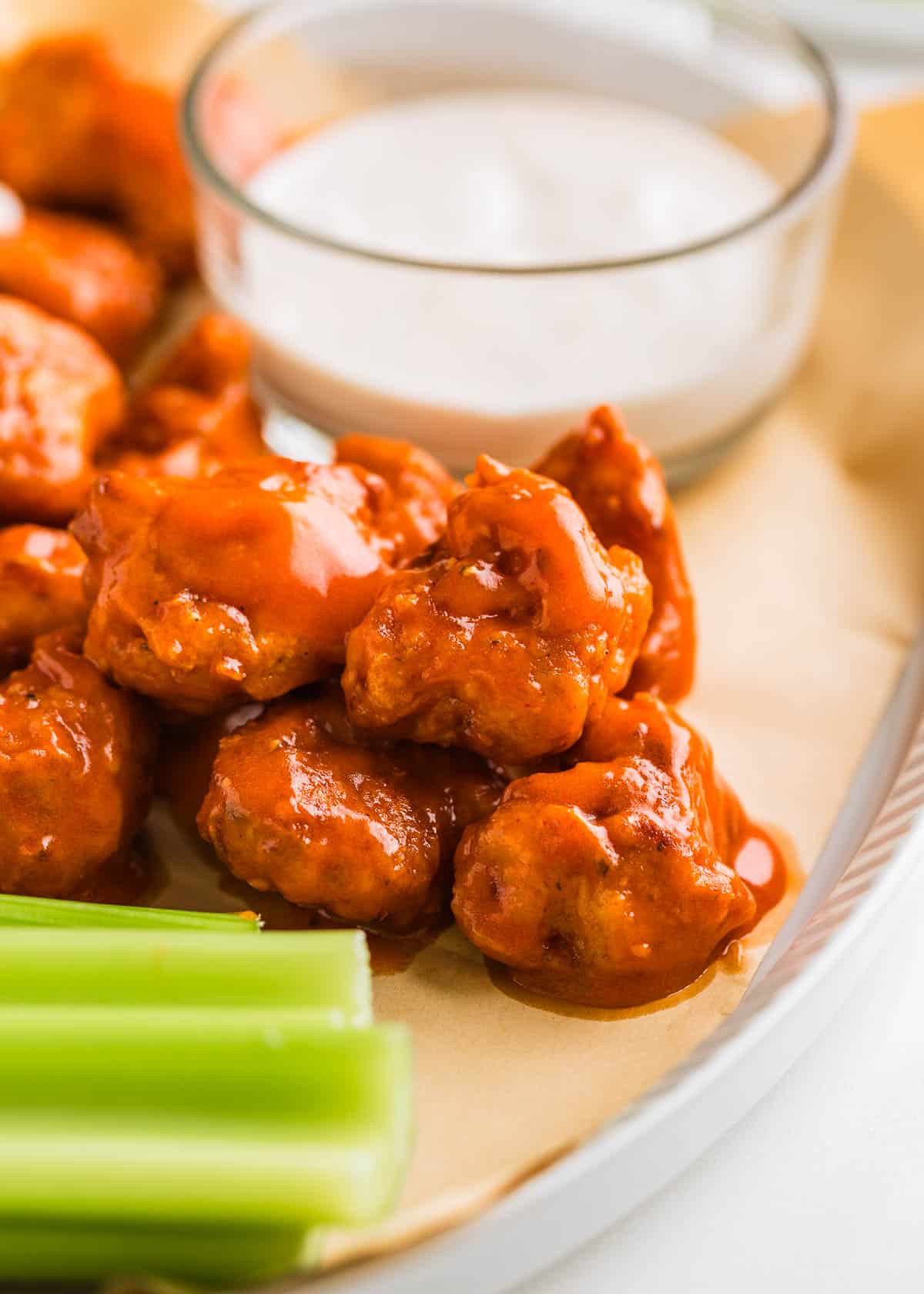 Boneless chicken wings on a serving plate with dip and celery.