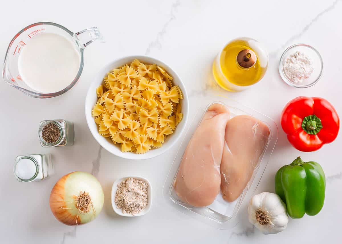 Chicken, fajita seasoning, bell peppers, pasta, cream and garlic on the counter.