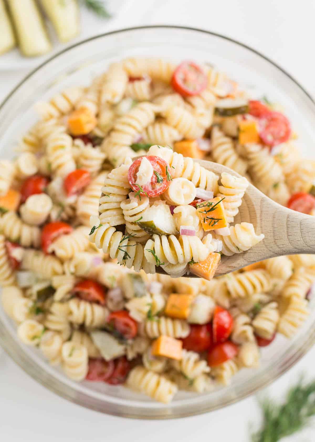 Spoonful of dill pickle pasta salad over the serving bowl.