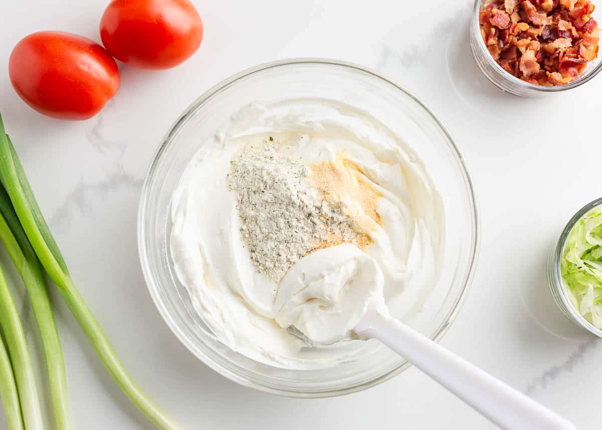 Mixing cream cheese and sour cream together in a bowl with seasonings.