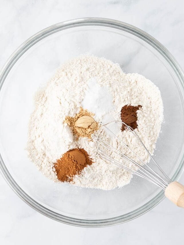 Flour and spices in a bowl with a whisk.