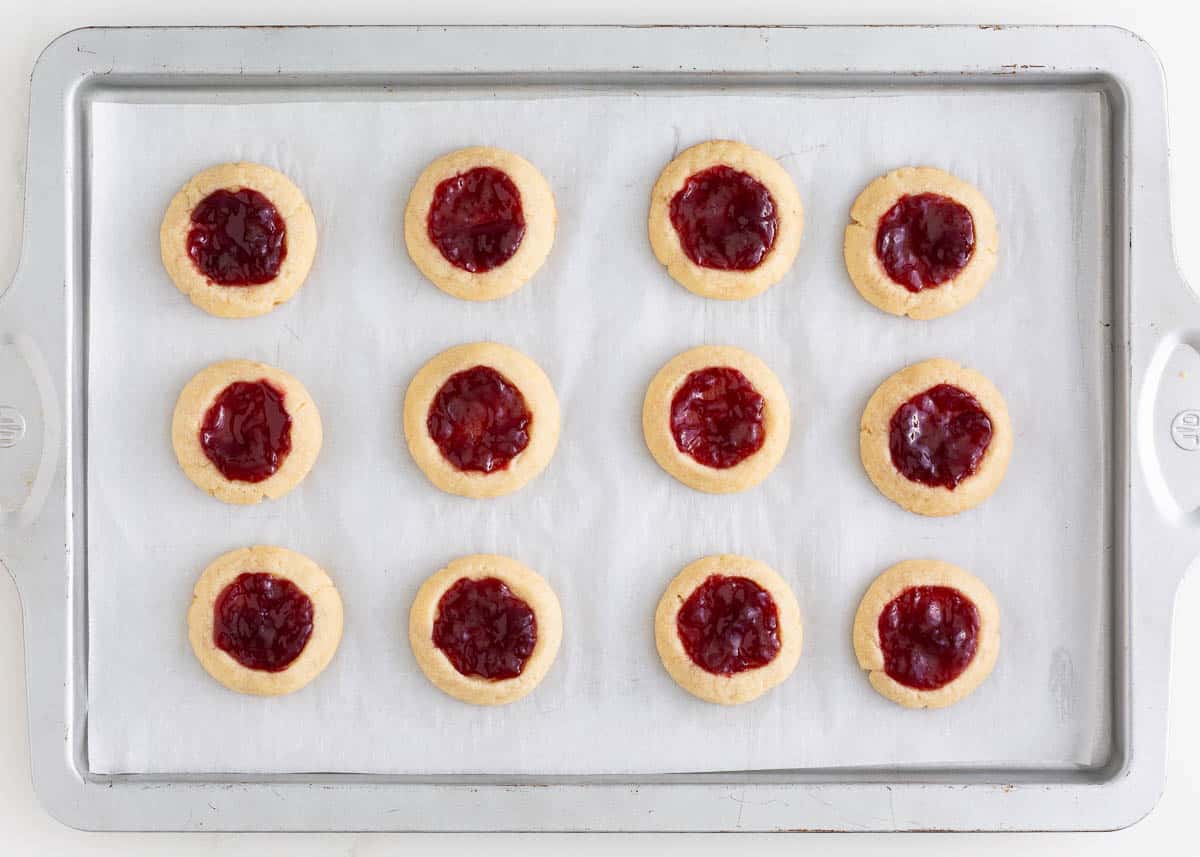 Raspberry thumbprint cookies on a baking sheet.