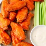 Oven baked buffalo wings on serving platter with celery and dip.