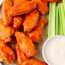 Oven baked buffalo wings on serving platter with celery and dip.