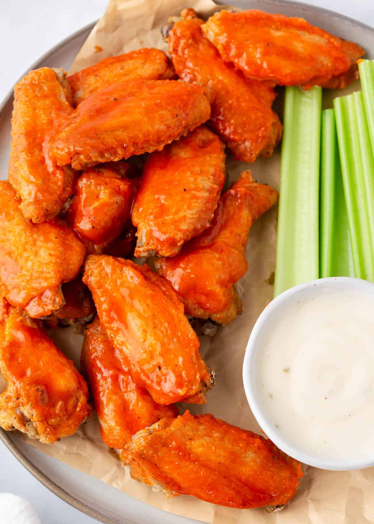 Oven baked buffalo wings on serving platter with celery and dip.