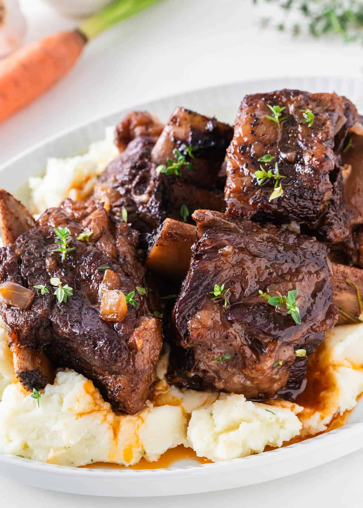 Cooked braised beef short ribs on a plate with mashed potatoes.