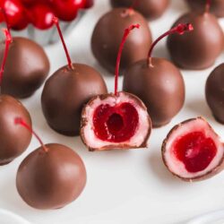 Chocolate covered cherry on a white plate.