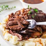 Red wine braised beef short ribs on a plate served over mashed potatoes.