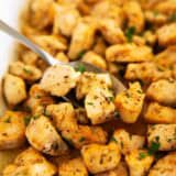 Baked chicken bites in baking dish with serving spoon.